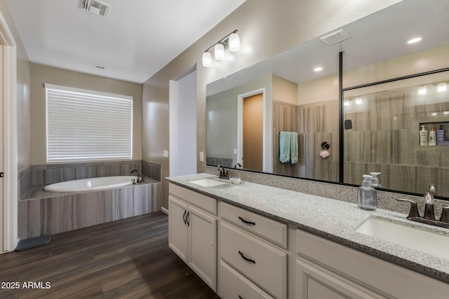 bathroom with double vanity, wood finished floors, visible vents, and a sink