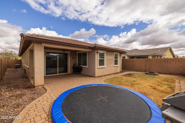 back of house featuring central AC unit, a fenced backyard, ceiling fan, stucco siding, and a patio area