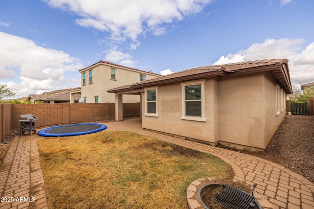 back of house featuring stucco siding, a tiled roof, a fenced backyard, and a patio