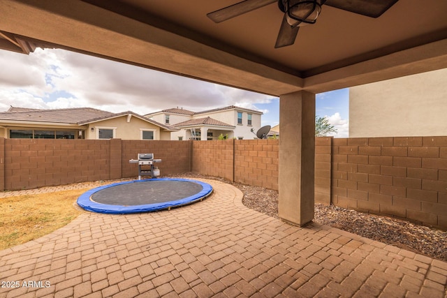 view of patio with ceiling fan, a trampoline, and a fenced backyard