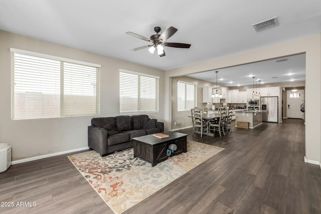 living area featuring baseboards, visible vents, and dark wood-style flooring