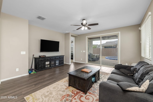 living area with a wealth of natural light, visible vents, baseboards, and wood finished floors