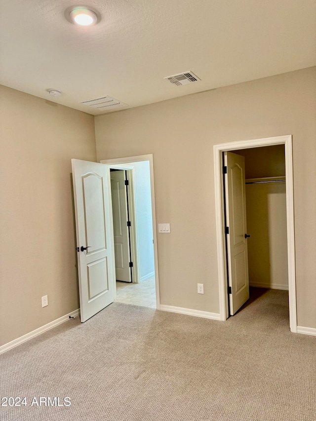 unfurnished bedroom with light carpet and a closet