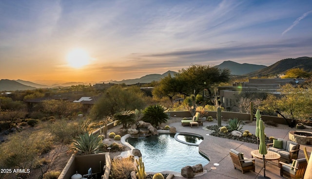 pool at dusk with an in ground hot tub, a mountain view, an outdoor pool, and a patio