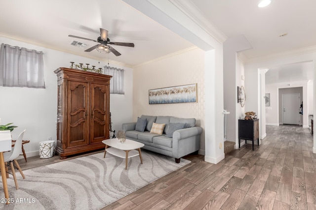 living room with visible vents, crown molding, baseboards, and wood finished floors