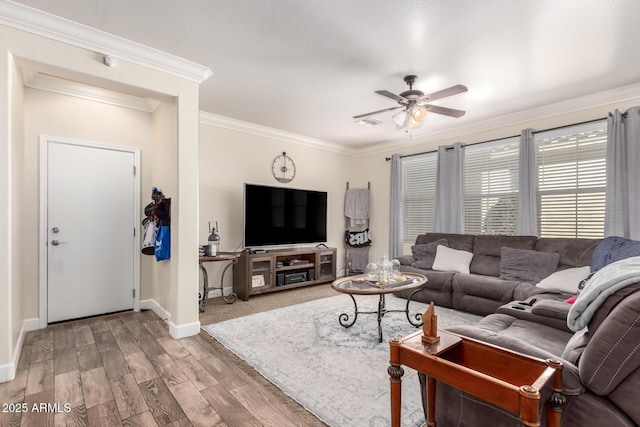 living area with ornamental molding, wood finished floors, a ceiling fan, and baseboards