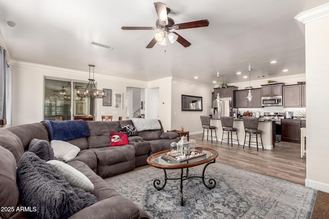 living room featuring visible vents, crown molding, and ceiling fan with notable chandelier