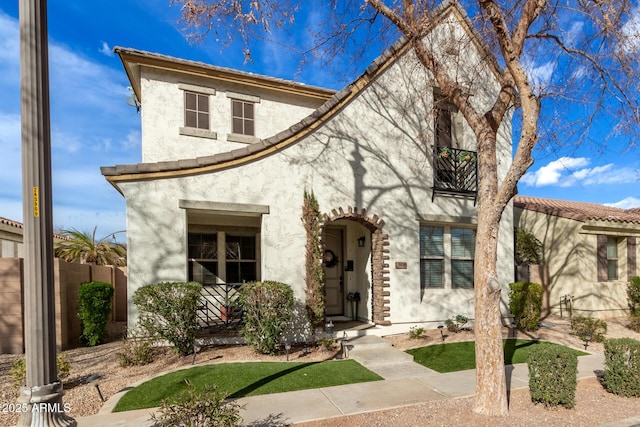 mediterranean / spanish home with fence and stucco siding