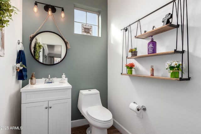 bathroom featuring toilet, baseboards, wood finished floors, and vanity