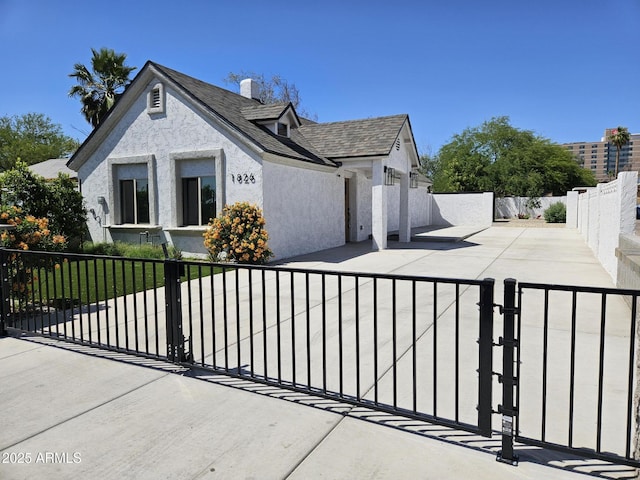 view of property exterior featuring stucco siding, a chimney, a gate, a patio area, and a fenced front yard