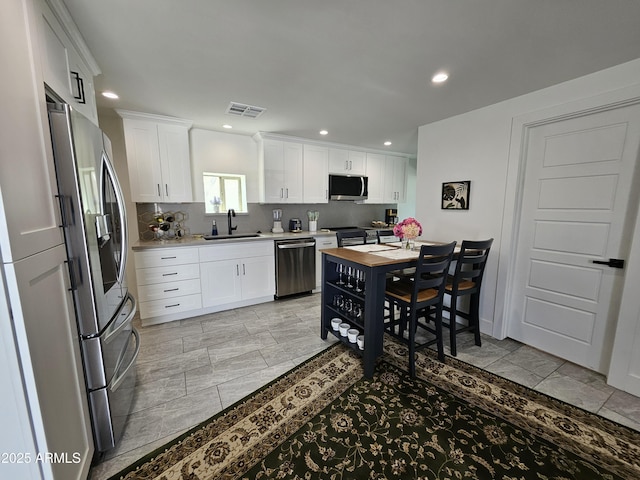 kitchen with visible vents, appliances with stainless steel finishes, a sink, white cabinets, and recessed lighting