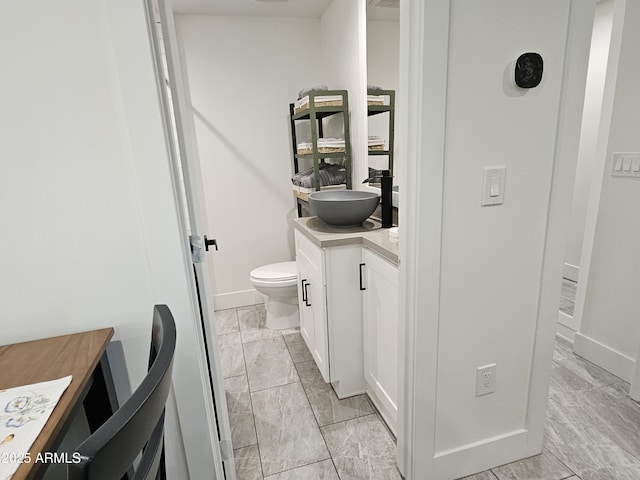 bathroom with vanity, baseboards, and toilet