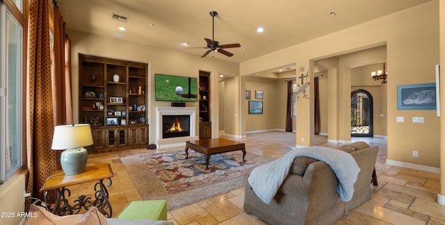 36813 N 109th Way, Scottsdale, AZ 85262 - living room featuring stone tile floors, arched walkways, a glass covered fireplace, ceiling fan, and recessed lighting