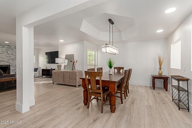 12015 S Tuzigoot Dr, Phoenix, AZ 85044 - dining space with light wood-type flooring, a tray ceiling, baseboards, recessed lighting, and a stone fireplace
