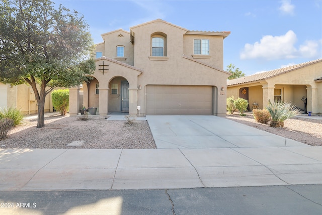 mediterranean / spanish house with a garage, a tile roof, concrete driveway, and stucco siding