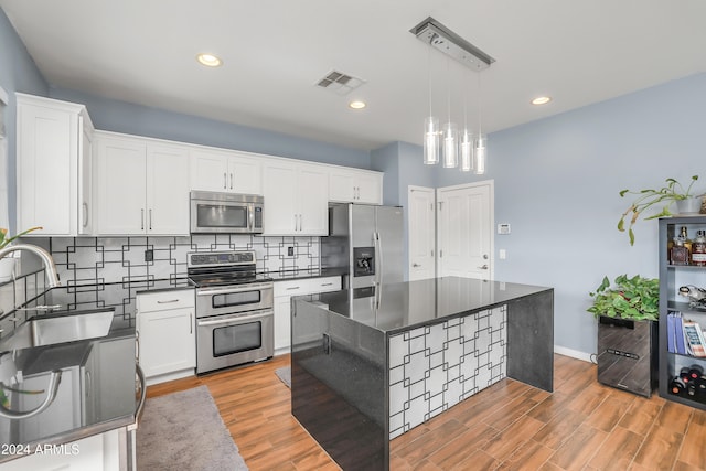 kitchen featuring white cabinets, appliances with stainless steel finishes, a kitchen island, and pendant lighting