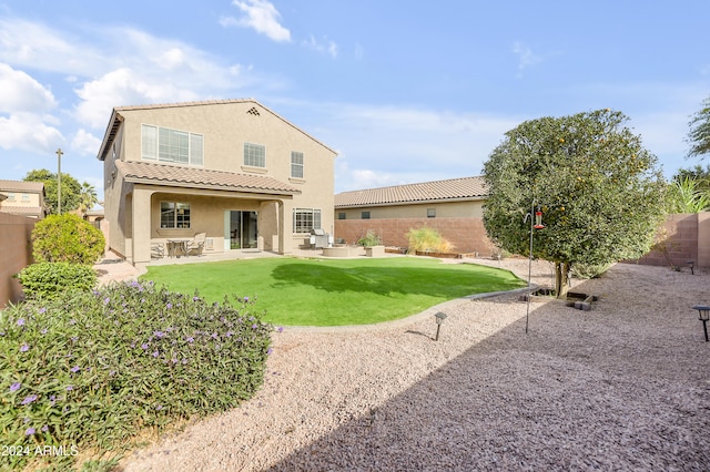 back of house with a tile roof, a patio, stucco siding, a lawn, and a fenced backyard