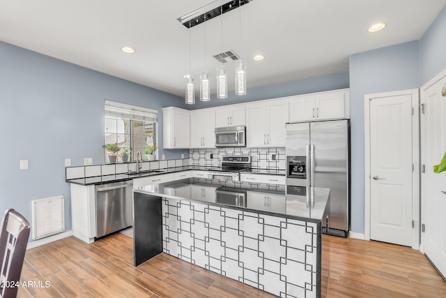 kitchen featuring white cabinetry, a center island, decorative light fixtures, appliances with stainless steel finishes, and light wood-type flooring