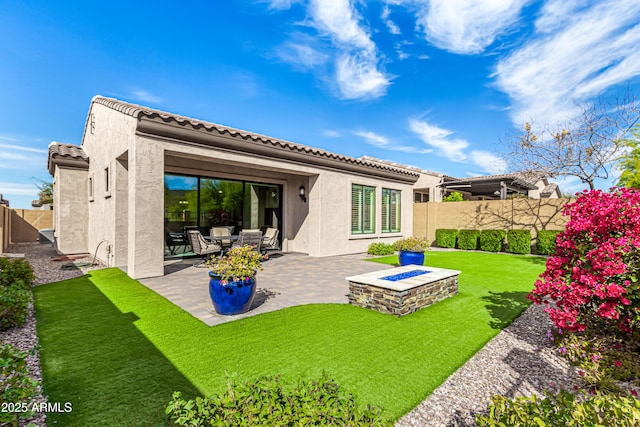 rear view of house featuring a yard, a patio area, and an outdoor fire pit