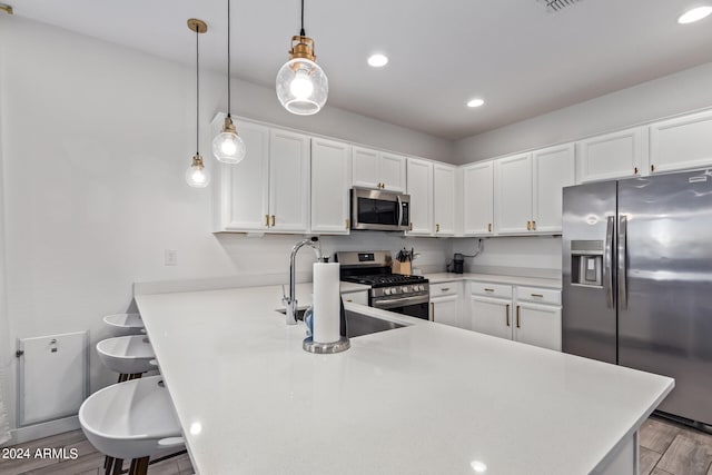 kitchen with light wood-type flooring, a kitchen bar, kitchen peninsula, stainless steel appliances, and white cabinets