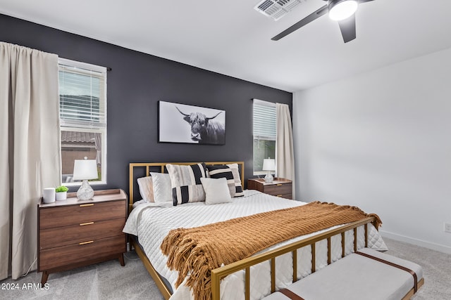 carpeted bedroom featuring multiple windows and ceiling fan