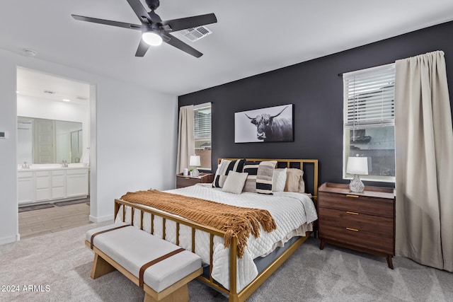 bedroom with ceiling fan, sink, light wood-type flooring, and ensuite bath