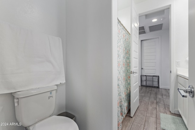 bathroom with toilet, vanity, and wood-type flooring