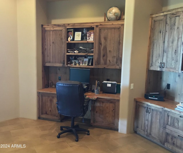 office space with built in desk and light tile flooring