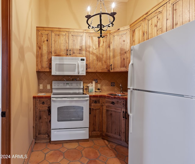 kitchen with decorative light fixtures, a notable chandelier, white appliances, sink, and light tile flooring