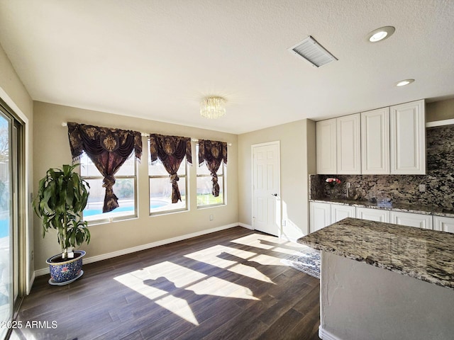 kitchen featuring white cabinetry, dark hardwood / wood-style floors, decorative backsplash, and dark stone countertops