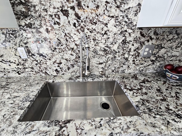 room details with light stone countertops, sink, and white cabinets