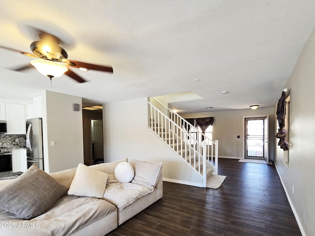 living room with dark hardwood / wood-style flooring, ceiling fan, and a textured ceiling