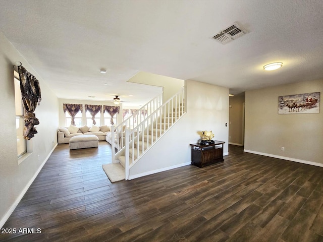 unfurnished living room with ceiling fan, dark hardwood / wood-style flooring, and a textured ceiling