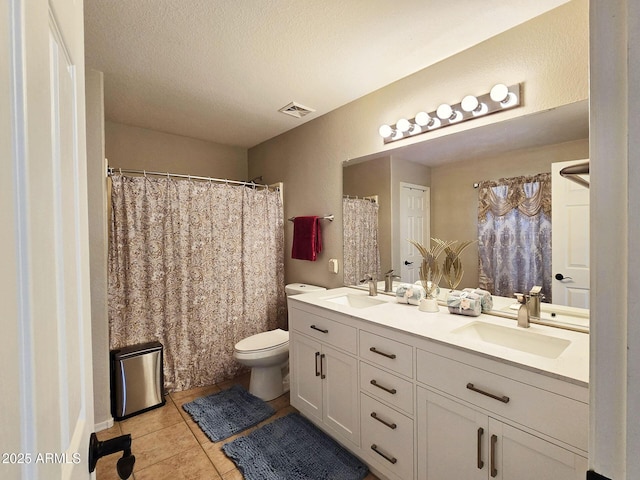 bathroom with tile patterned floors, vanity, toilet, and a textured ceiling