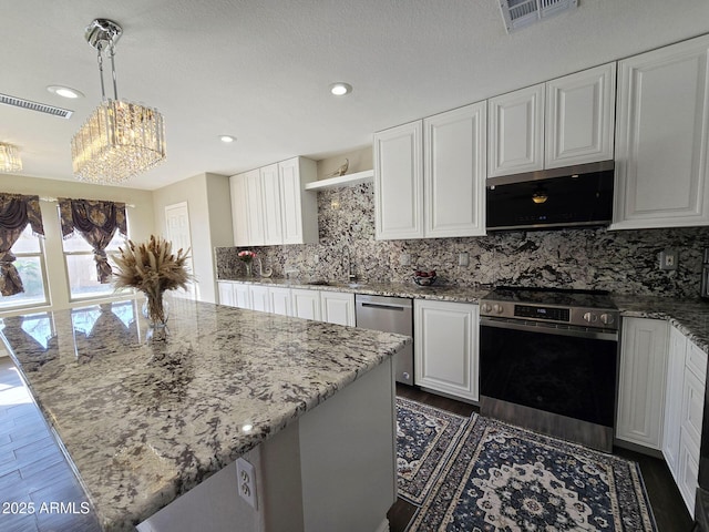 kitchen with hanging light fixtures, appliances with stainless steel finishes, and white cabinets