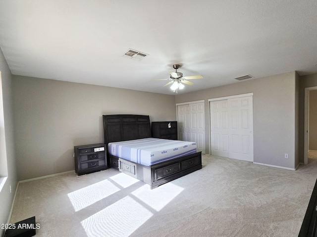 unfurnished bedroom with multiple closets, ceiling fan, and light carpet