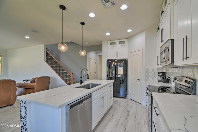 kitchen featuring pendant lighting, white cabinetry, an island with sink, sink, and stainless steel appliances