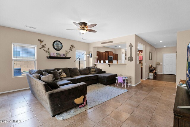 living room featuring light tile patterned floors, a wealth of natural light, ceiling fan, and visible vents