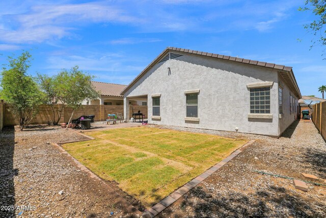 back of house with a fenced backyard, a patio area, stucco siding, and a yard