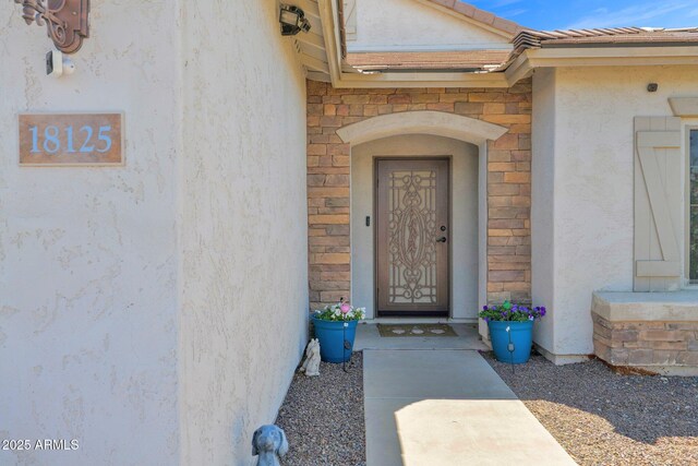 entrance to property with stone siding and stucco siding