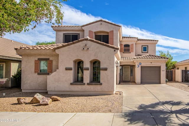 mediterranean / spanish-style home with a garage, fence, driveway, a tiled roof, and stucco siding