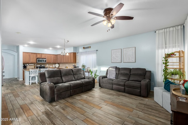 living room with ceiling fan with notable chandelier and wood finished floors