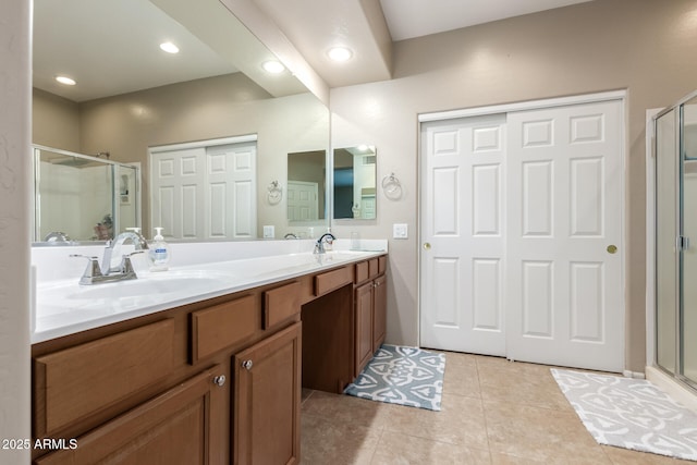 bathroom with double vanity, a stall shower, tile patterned flooring, and a sink