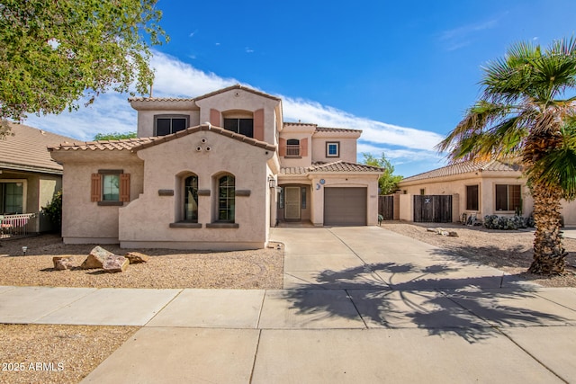 mediterranean / spanish-style house featuring a tile roof, stucco siding, fence, a garage, and driveway