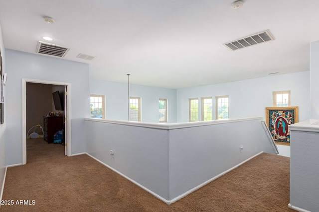 hallway with carpet, visible vents, and an upstairs landing