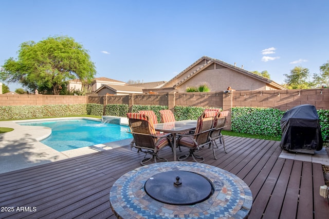 view of swimming pool featuring an outdoor fire pit, a fenced in pool, area for grilling, a fenced backyard, and a deck