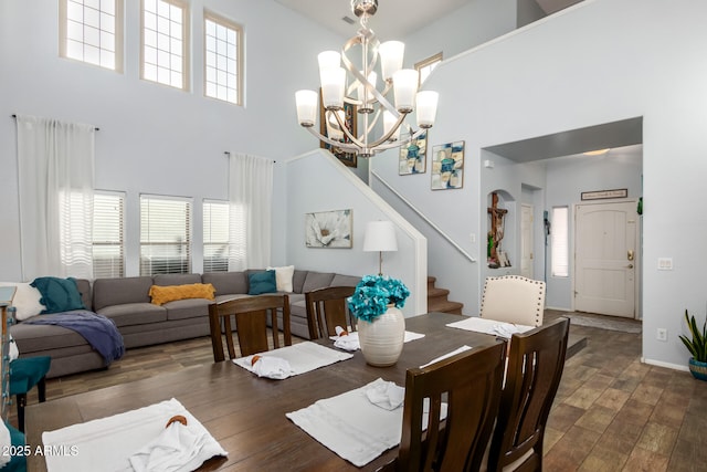 dining room featuring stairs, a high ceiling, a chandelier, and wood finished floors