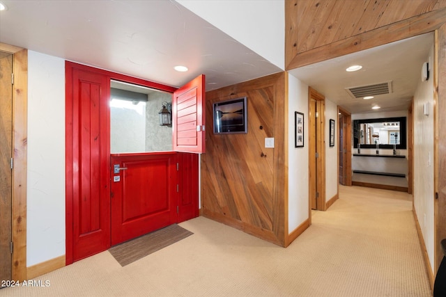 interior space with light carpet and wood walls