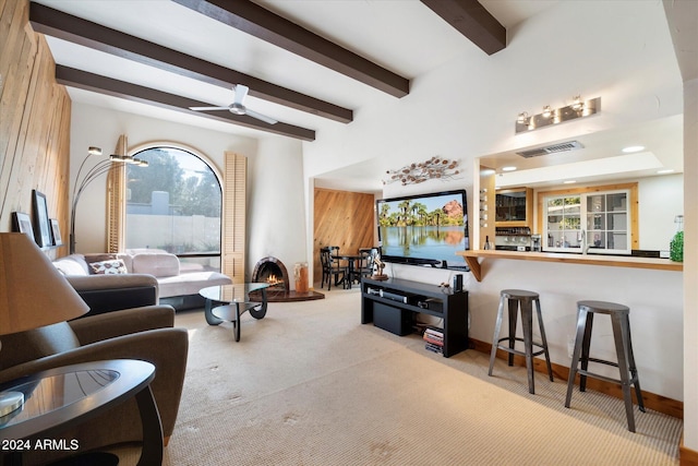 living room with a wealth of natural light, beamed ceiling, ceiling fan, and light carpet