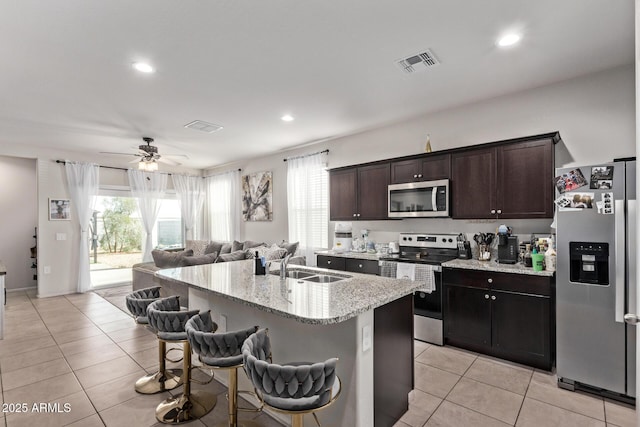 kitchen with a kitchen island with sink, sink, light tile patterned flooring, and appliances with stainless steel finishes